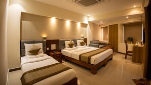 A hotel room with two beds, a desk, a chair, and a bathroom. - Metro Plaza Hotel (Mangaluru)
