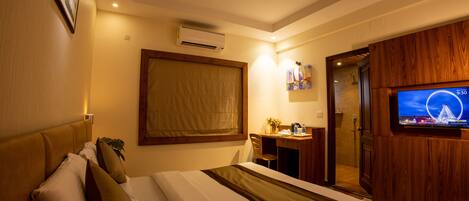 A hotel room with a bed, a desk, a chair, a television, and a ceiling fan.