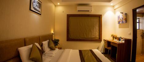 Una habitación de hotel con cama, escritorio, silla, ventilador de techo y aire acondicionado.