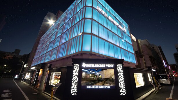 Hotel moderno com fachada de vidro e placa indicando inauguração em 2019.
