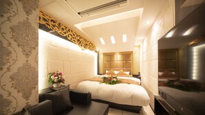 Quarto de hotel moderno com uma cama grande, um sofá, uma TV e um painel decorativo na parede.