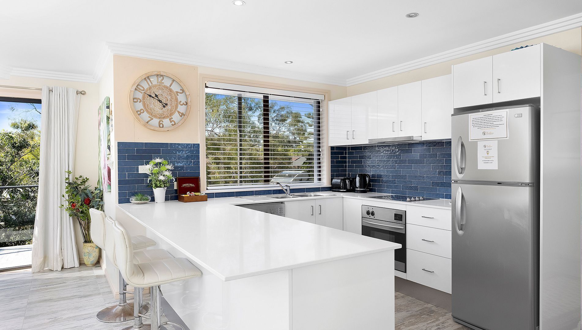 A modern kitchen with white cabinets, a stainless steel refrigerator, and a large island.