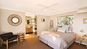 A bedroom with a bed, a chair, a bedside table, a window, and a ceiling fan. - Stunning Home With Spectacular Views (Coolum Beach)