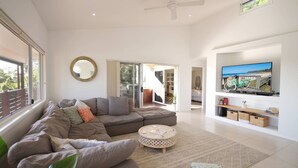 A modern living room with a sectional sofa, a round coffee table, and a television on a white wall. - Stunning Home With Spectacular Views (Coolum Beach)