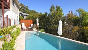 A swimming pool with two lounge chairs and a wooden deck. - Stunning Home With Spectacular Views (Coolum Beach)