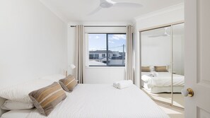 Ein Schlafzimmer mit Bett, Fenster, Deckenventilator und einer Schiebetür.
