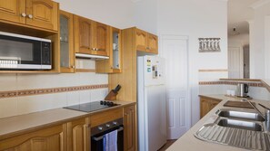 A kitchen with wooden cabinets, a microwave, a refrigerator, and a sink. - Absolute Oceanfront - Portovenere Fishermans Bay - Watch The... (FISHERMANS BAY)
