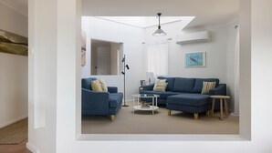 Un salón moderno con un sofá azul, una lámpara de pie y una mesa de centro.