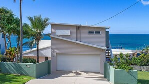 A two-story house with a garage, a small window on the upper floor, and a view of the ocean.
