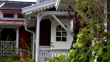 Ett traditionellt hus med en vit veranda, en röd dörr och ett fönster.