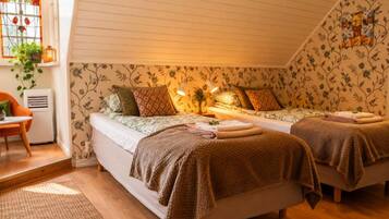 A cozy bedroom with two beds, a chair, and a window with a plant.