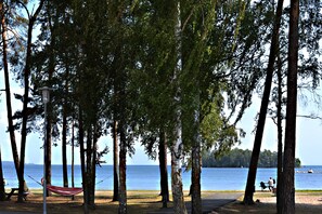 A park with a hammock, a bench, and a lake view. - Nymans Bed & Breakfast (Karlsborg)