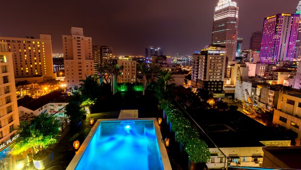 A rooftop pool with a view of a cityscape at night, including illuminated buildings and a clear sky. - Roseland Sweet Hotel (Ho Chi Minh City)