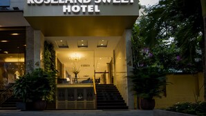 The exterior of the Roseland Sweet Hotel with a modern design, a staircase leading to the entrance, and potted plants around the entrance area. - Roseland Sweet Hotel (Ho Chi Minh City)