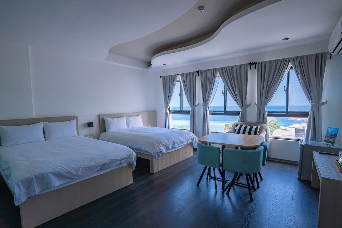 Una habitación de hotel con dos camas, una mesita y una silla.