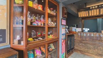 A candy store with wooden display cases filled with various snacks and a menu board above the counter.