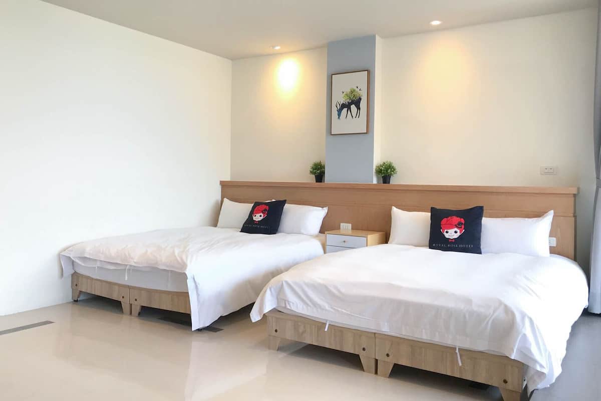 Habitación de hotel con dos camas, una mesita de noche, una pequeña mesa y un cuadro colgado en la pared.