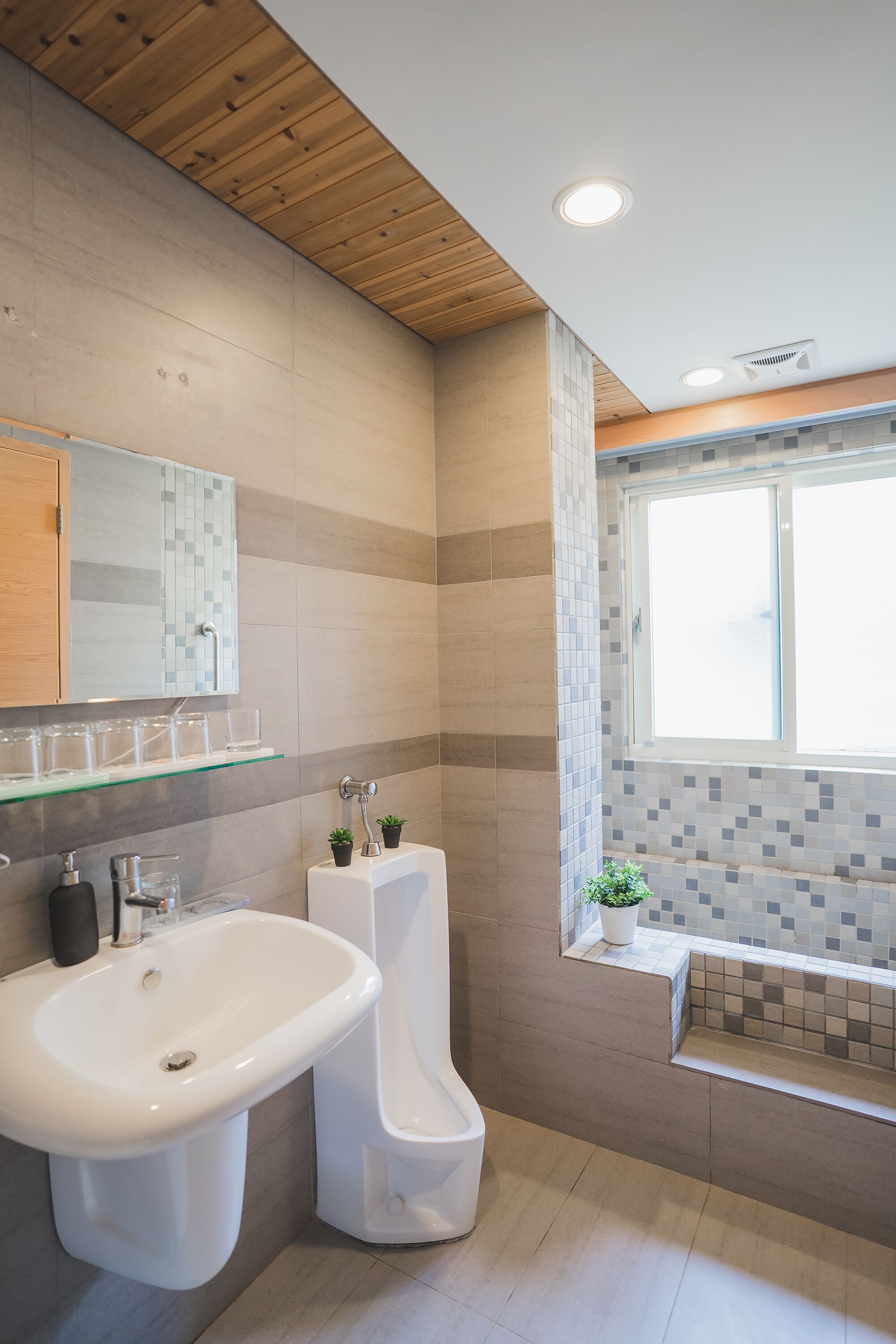 Une salle de bain moderne avec un plafond en bois, un grand lavabo, des toilettes et une fenêtre.