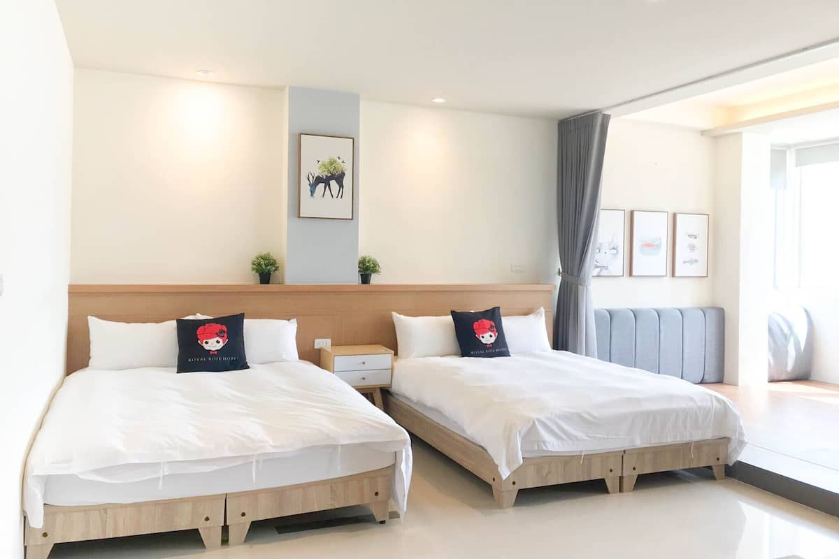 Habitación de hotel con dos camas, una mesita de noche, una pequeña mesa y una ventana con cortinas.