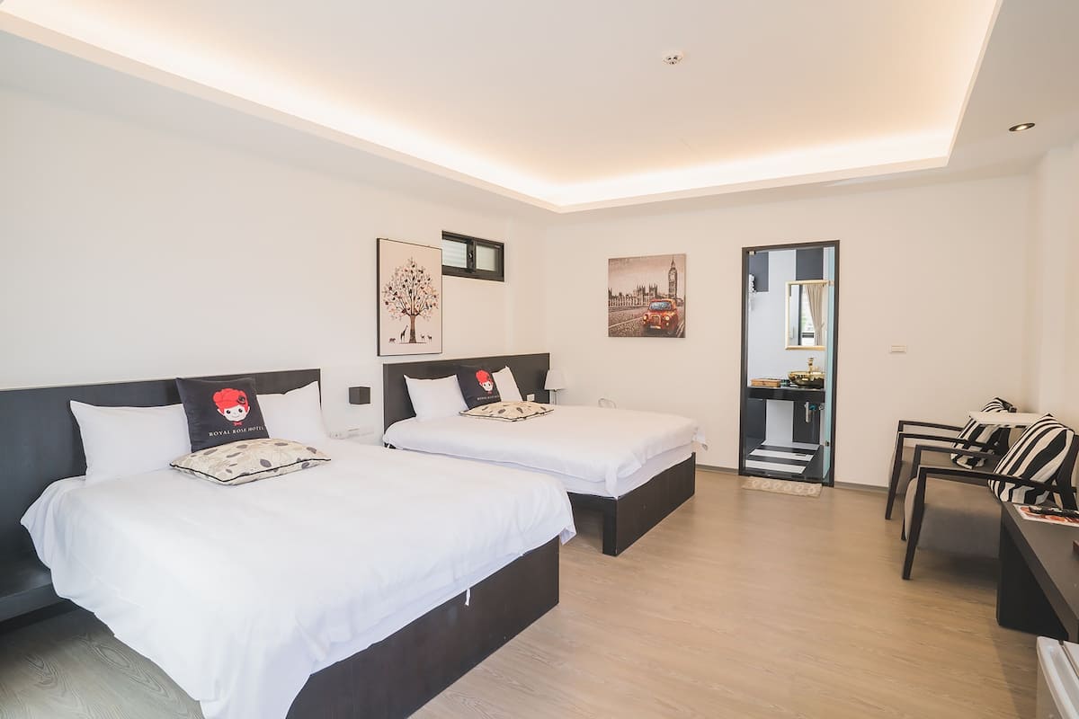 Habitación de hotel con dos camas, un escritorio y una silla. Hay un cuadro en la pared y una puerta que da al baño.