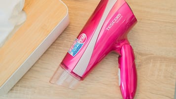 A pink hairdryer with a transparent nozzle on a wooden surface.