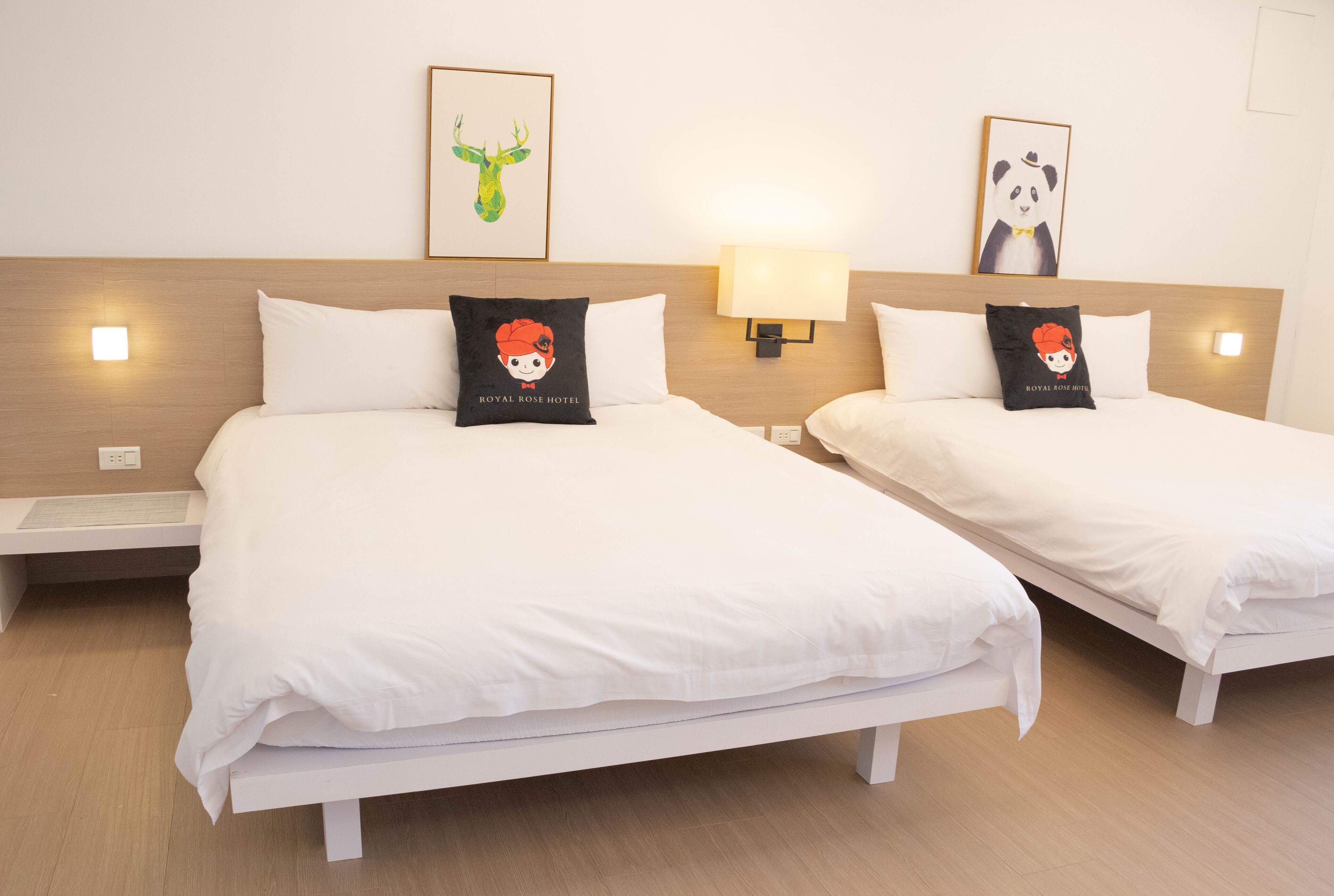 Une chambre d’hôtel avec deux lits, chacun agrémenté d’un oreiller orné d’un personnage de dessin animé. Des appliques murales et des œuvres d’art encadrées sont disposées au-dessus des lits.