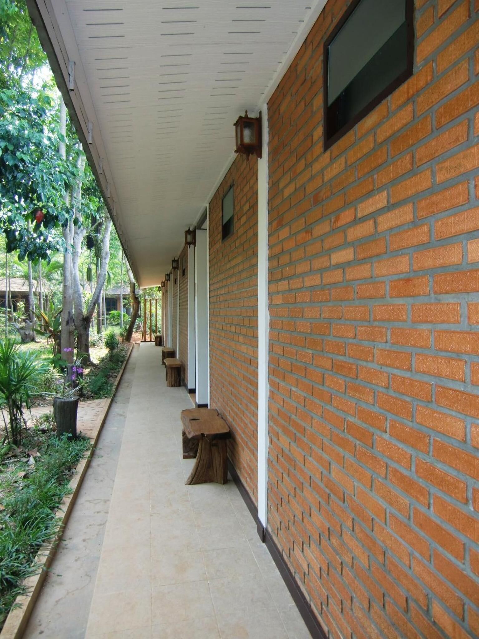 A covered walkway with brick walls and wooden benches.