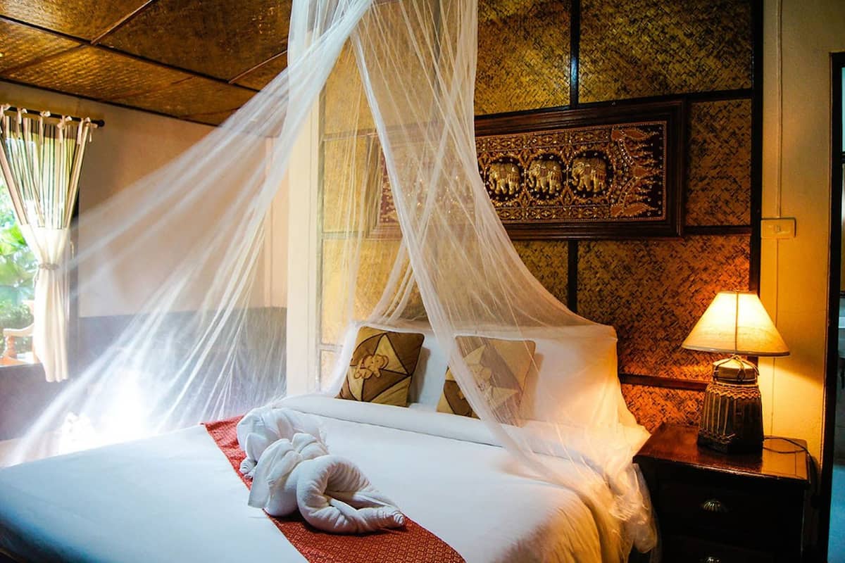 A bed with a canopy, pillows, and a bedside table with a lamp.