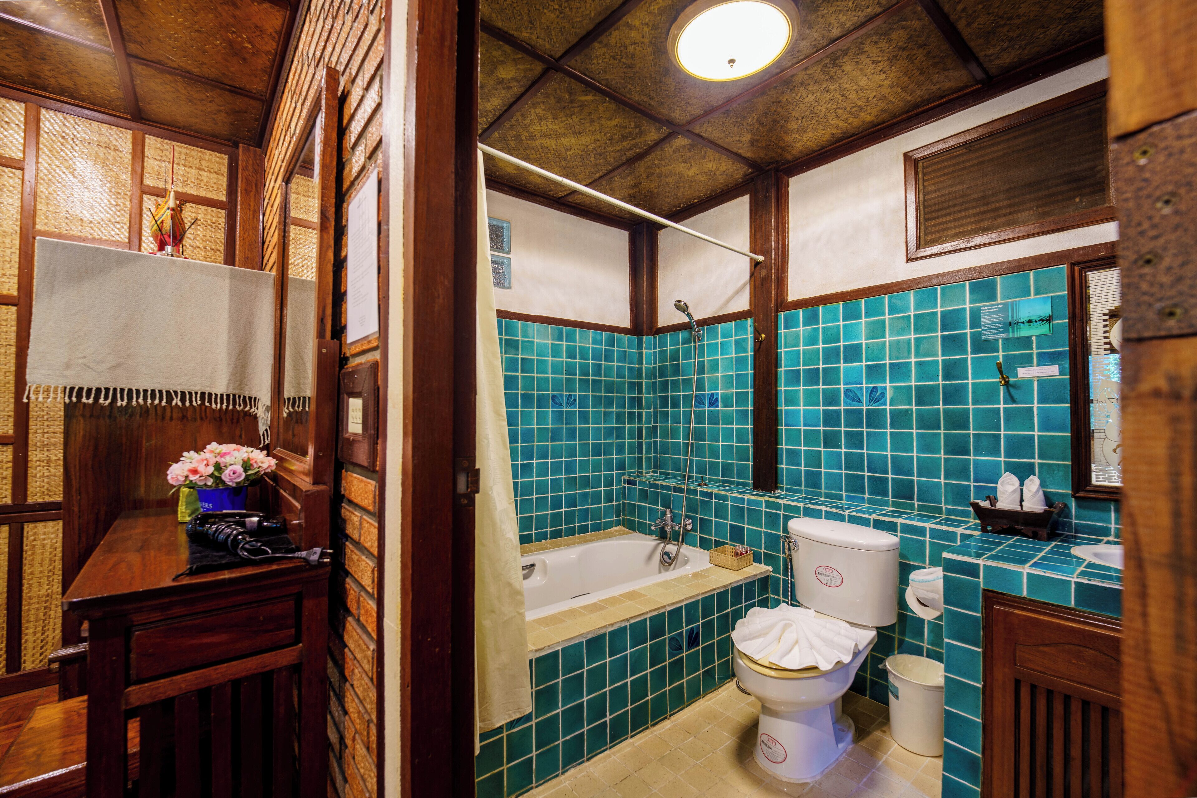 A bathroom with a bathtub, toilet, and sink, featuring wooden walls and blue-tiled walls.