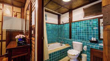 A bathroom with a bathtub, toilet, and sink, featuring wooden walls and blue-tiled walls.