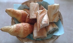 A basket containing various types of bread, including baguettes and croissants. - Chambres d'hotes du Jay (La Guerche-sur-l'Aubois)