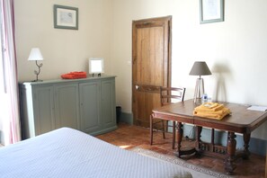 A room with a bed, a wooden table with a chair, a green cabinet, a wooden door, and two wall-mounted lamps. - Chambres d'hotes du Jay (La Guerche-sur-l'Aubois)