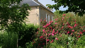 A building with a garden featuring blooming pink flowers and green foliage. - Chambres d'hotes du Jay (La Guerche-sur-l'Aubois)