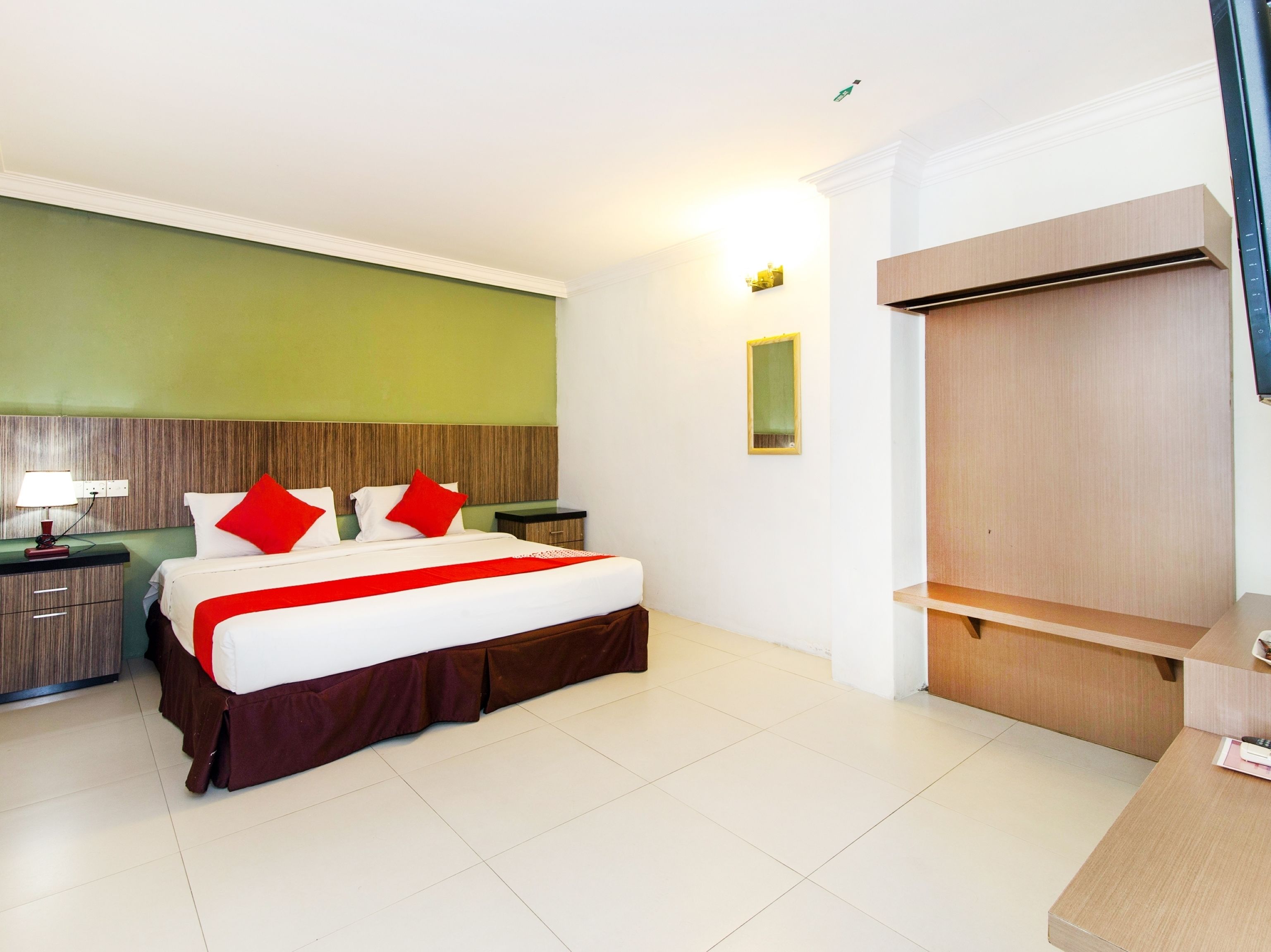 Ein Hotelzimmer mit Bett, Nachttischen, einem Schrank und einem kleinen Fenster.