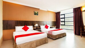 A hotel room with two beds, a large window with curtains, and a small table with a lamp. - Super OYO 443 Crystal City Hotel (Kuantan)