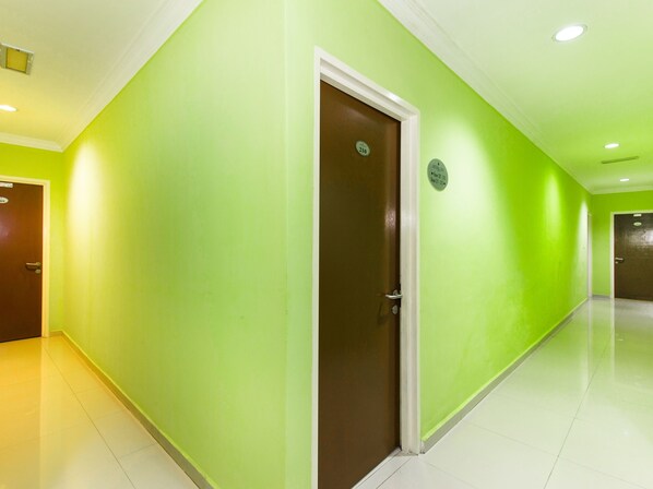Un couloir aux murs verts et à la porte marron.