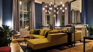 Een moderne woonkamer met een modulaire bank, een eethoek en een groot raam met gordijnen.