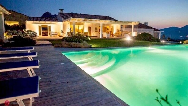Une maison moderne dotée d’une piscine, d’un patio couvert et offrant une vue sur les montagnes.