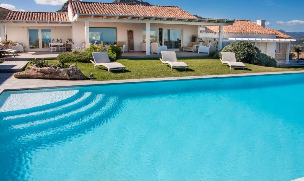 A modern house with a swimming pool, outdoor seating, and a mountain view.