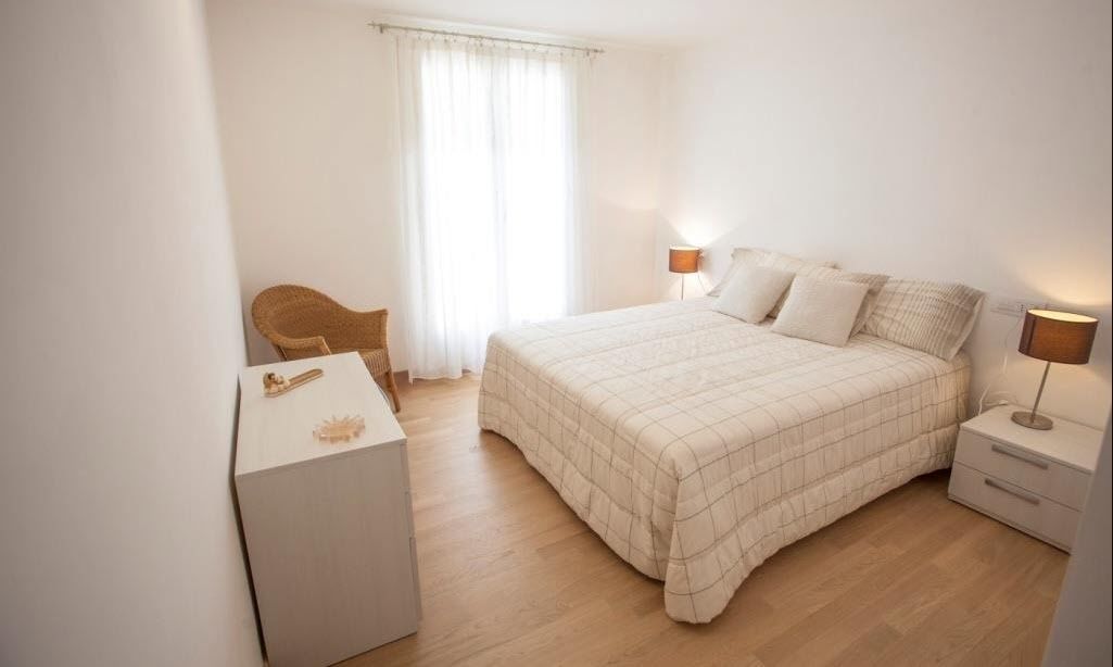 A bedroom with a bed, bedside tables, a chair, and a desk.