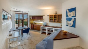 A modern kitchen with a dining area, large windows, and a view of the outdoors.