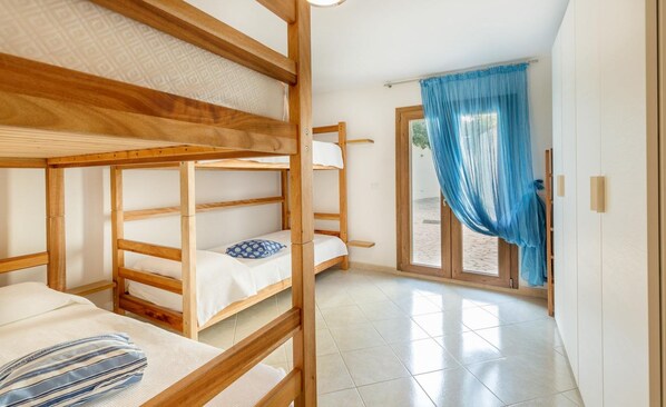 A room with bunk beds, a small table, and a window with blue curtains.