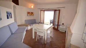 Una sala de estar acogedora con un sofá, una mesa de comedor y sillas. Cuenta con un balcón con una silla y una mesita.