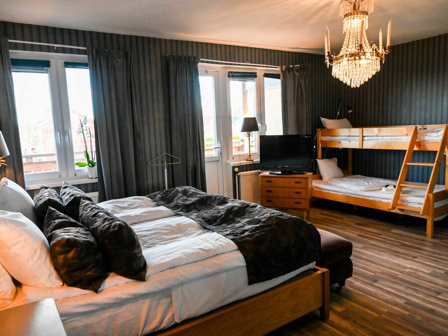 A bedroom with a large bed, a bunk bed, a chandelier, and a TV.