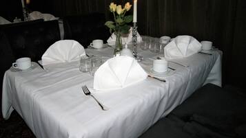 Ein Tisch, festlich gedeckt für ein formelles Abendessen, mit weißen Tischdecken, Servietten und einer Kerzenarrgementierung.