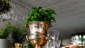 A display case with various food items and a large copper pot with green plants. - Palace Hotell (Hultsfred)