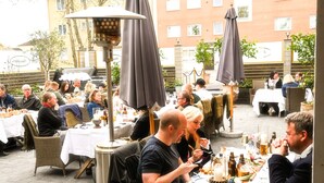 An outdoor dining area with tables and chairs, umbrellas, and a variety of dishes and drinks. - Palace Hotell (Hultsfred)