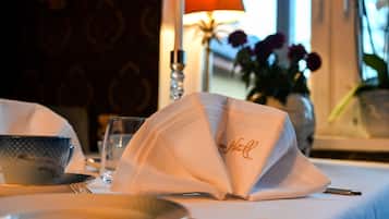 A beautifully set dining table awaits your meal, complete with a crisp tablecloth, fine china, and a vase of fresh flowers.