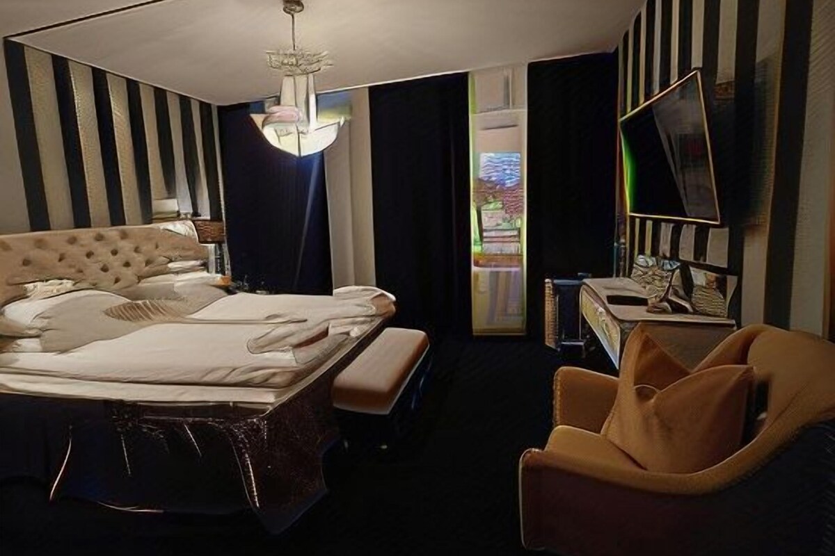 Una habitación de hotel con una cama grande, un escritorio, una silla y un televisor.