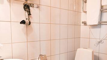 A bathroom with a toilet, sink, and a glass shelf with toiletries.